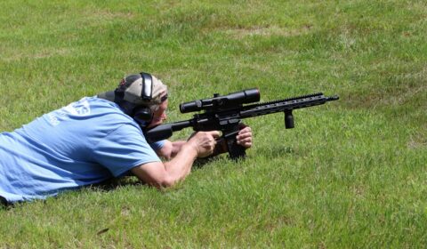 Shooter in prone position aiming a rifle for long range target shooting